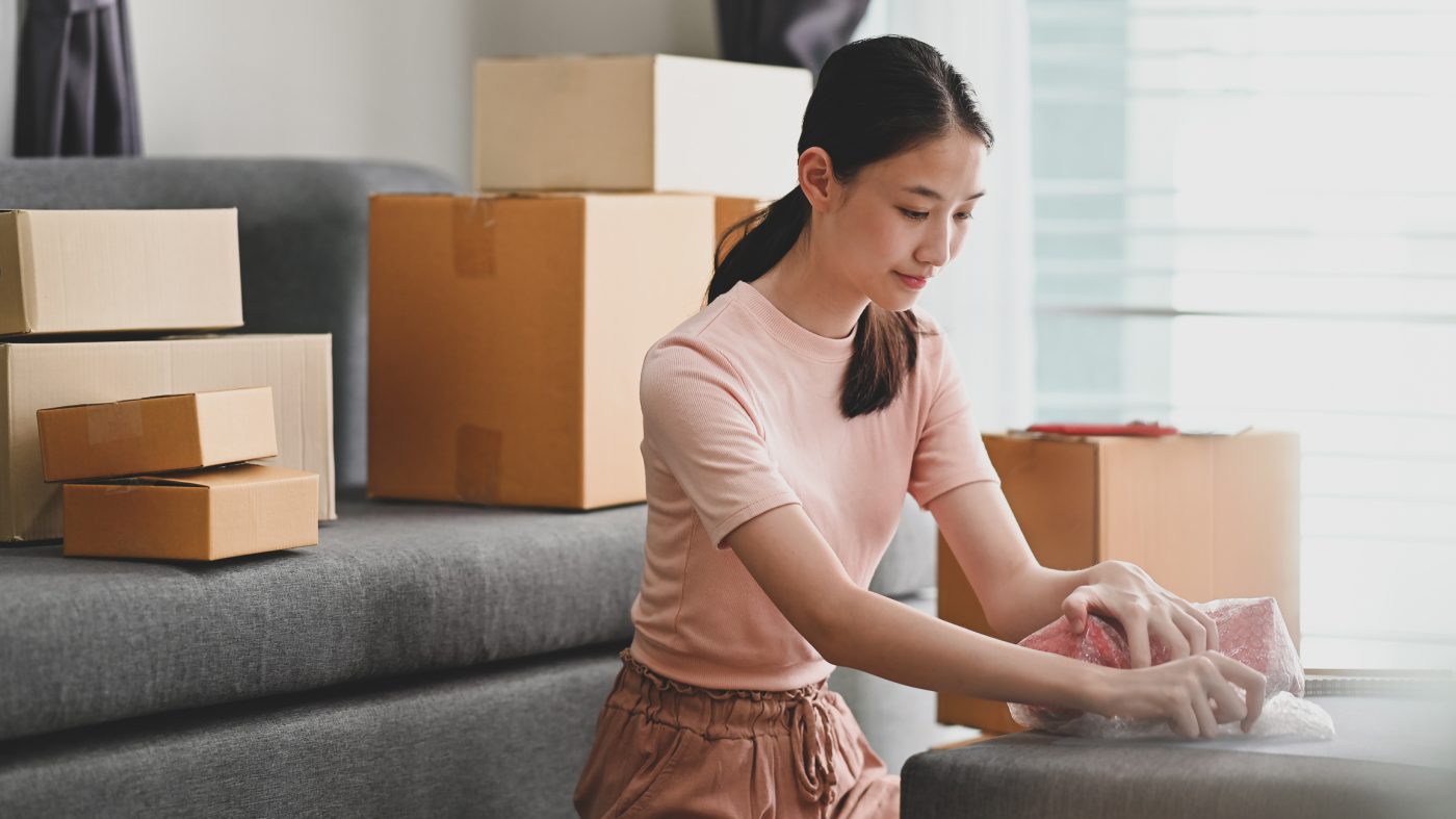 Online small business owner packing drop product on box.