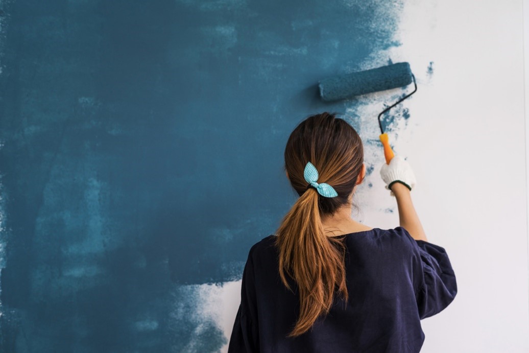 women painting a white wall with blue paint