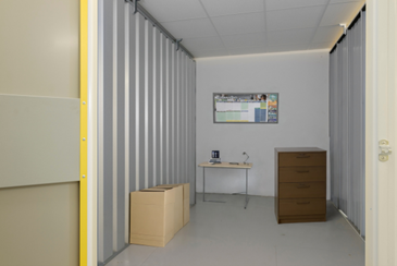 storage unit with a desk, boxes, drawers, and a calendar in it