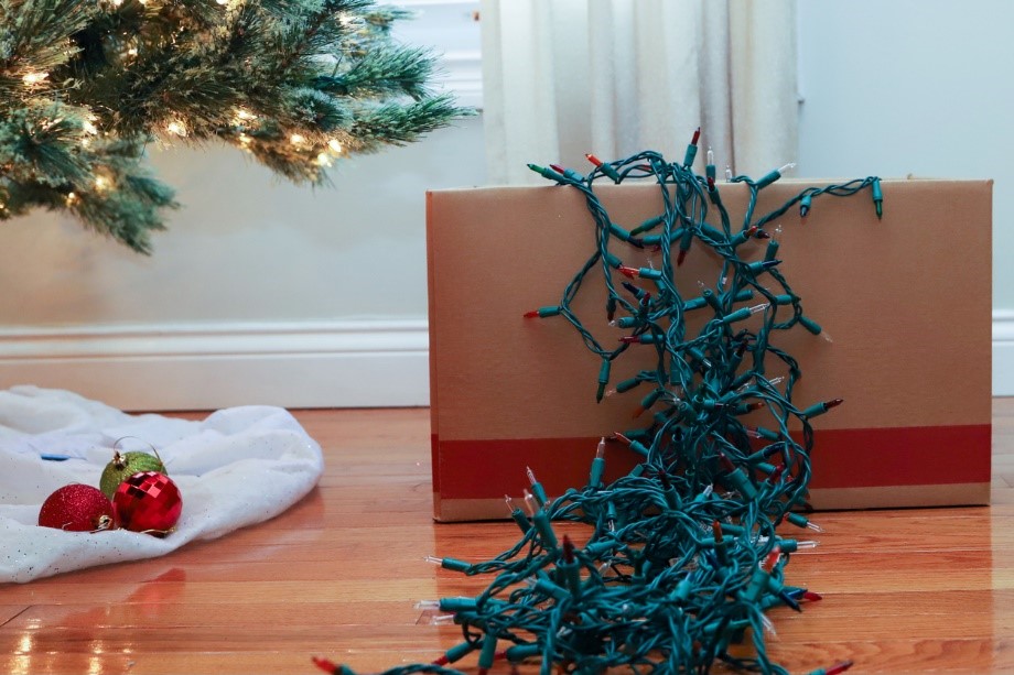christmas lights pouring out of a cardboard box under a christmas tree