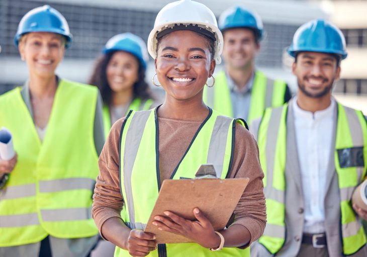 Happy construction workers facing camera and smiling in high-vis and hard hats